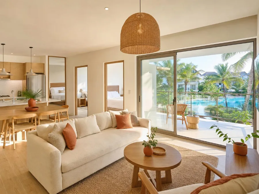 Living room of a two-bedroom apartment opening onto a balcony above a pool
